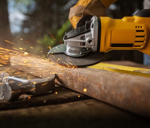 Worker works with saw in production. Metal processing with angle grinder. Sparks in metalworking.